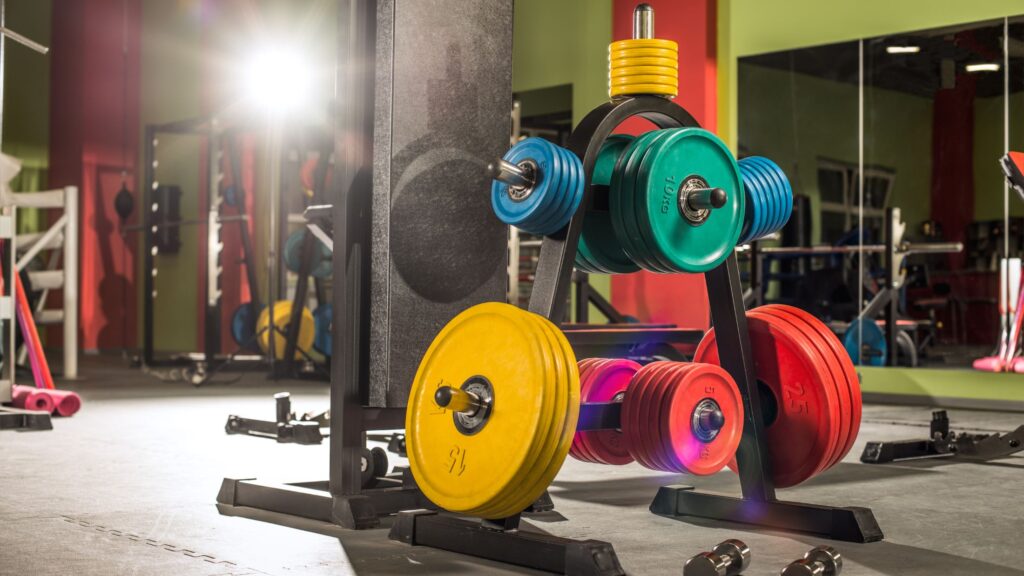 Colorful gym weight plates in a well-lit gym room.