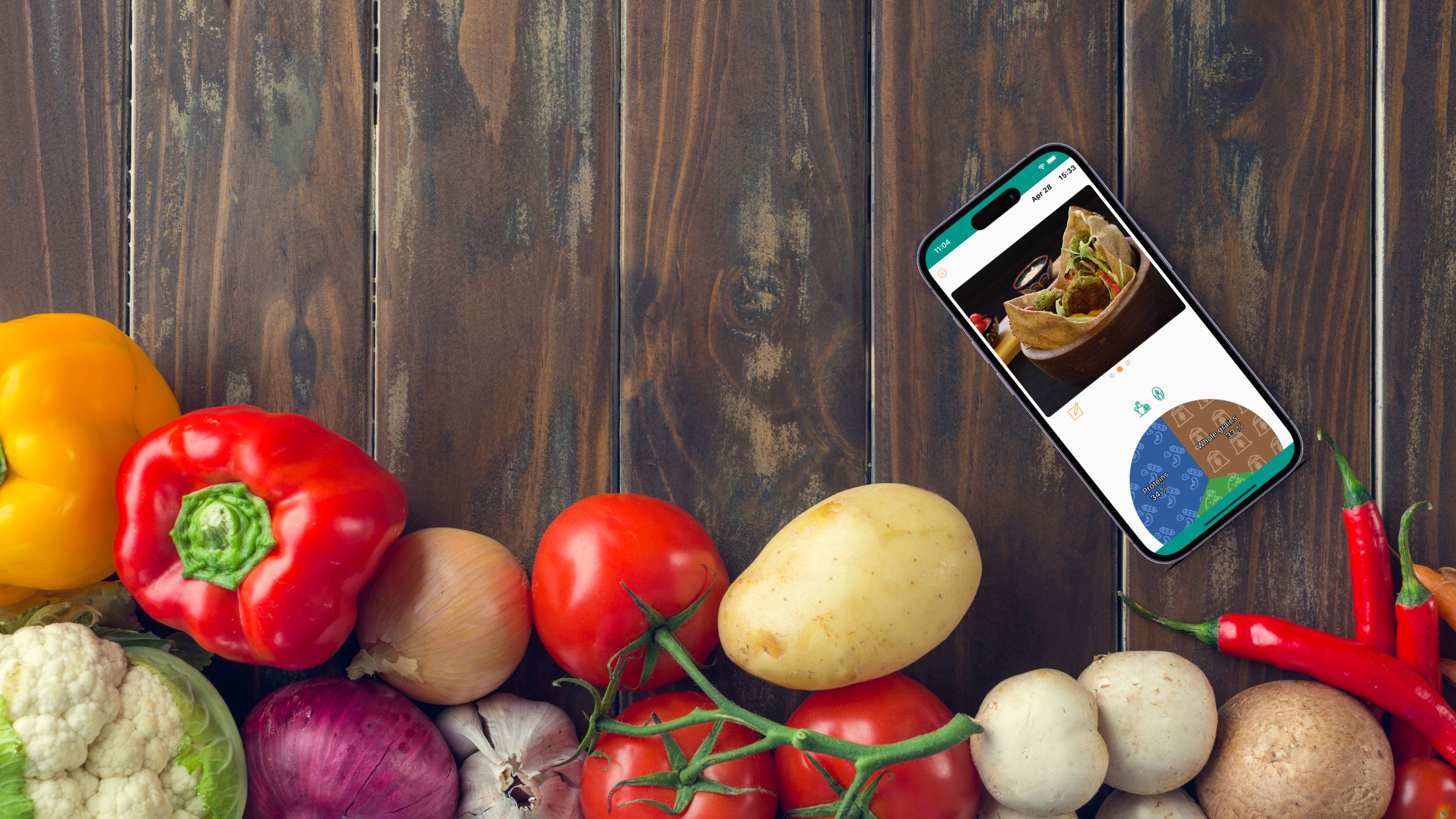 A smartphone displaying the JustaPlate food diary app laying alongside an assortment of vibrant fresh vegetables.