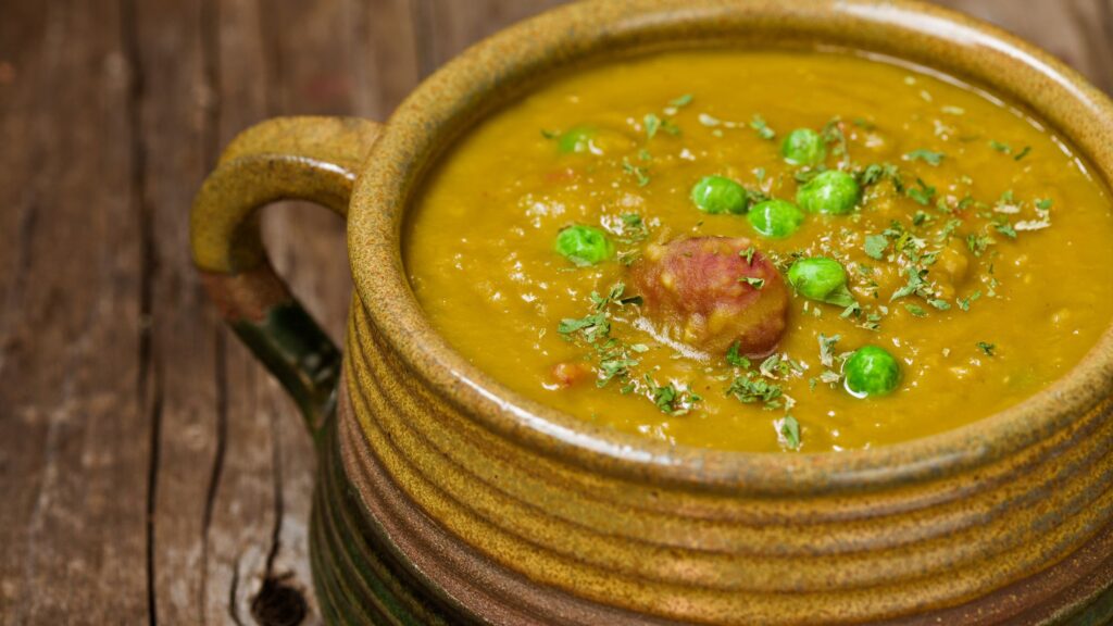 A bowl of split pea soup topped with peas and cilantro.
