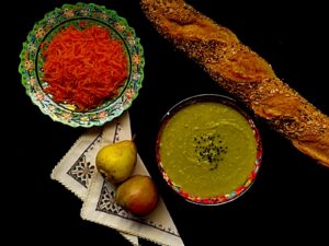 split pea soup served in a bowl with bread, carrots and some fruits